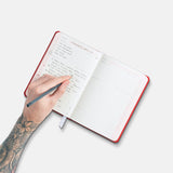 Hand writing in open Savor Recipe Journal.